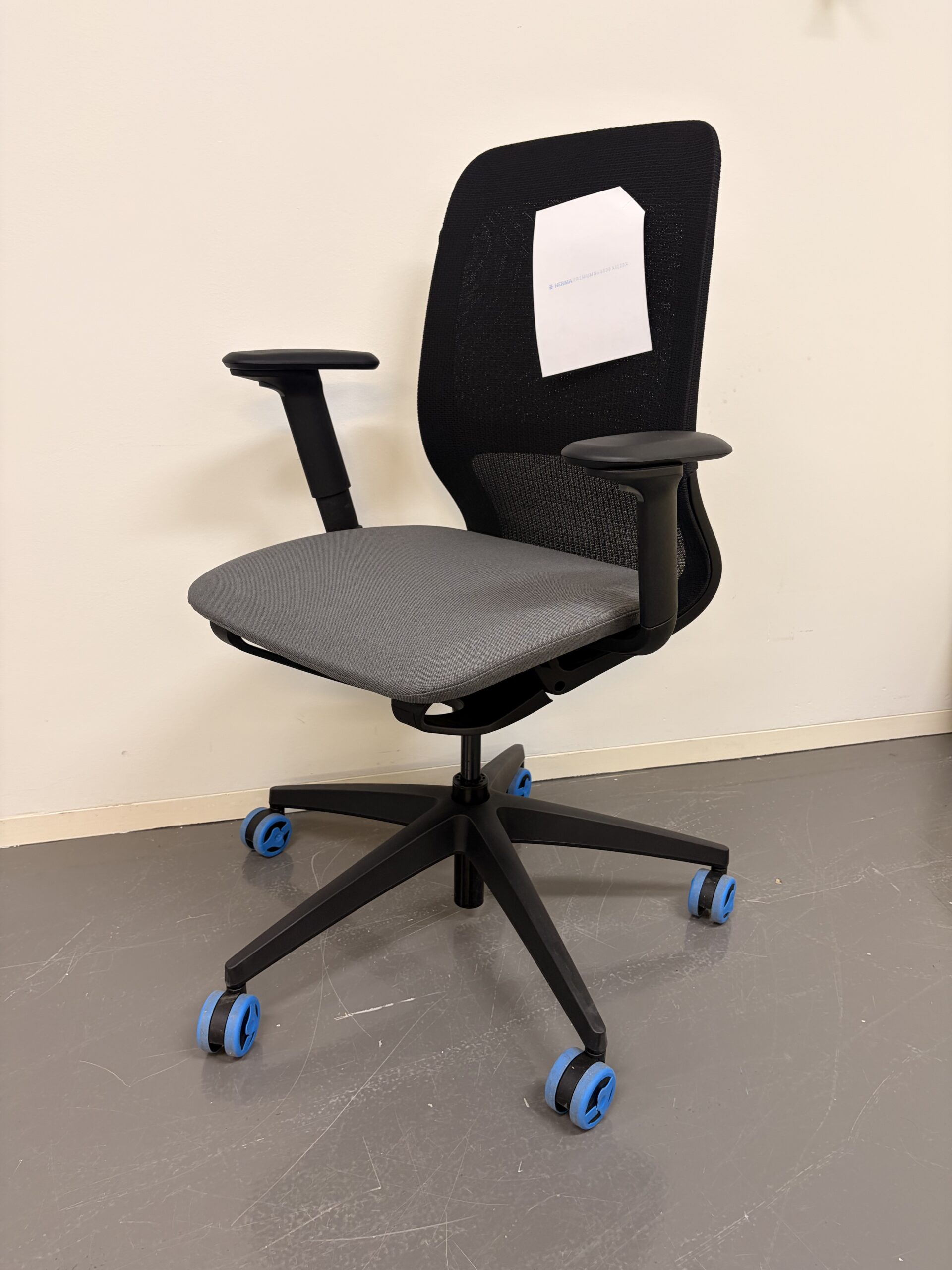 Bürostuhl mit schwarzer Netzrückenlehne, grauem Sitzpolster und schwarzen Armlehnen schräg