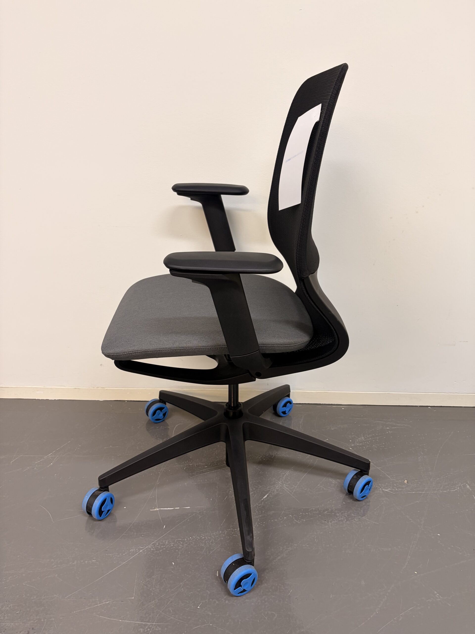Bürostuhl mit schwarzer Netzrückenlehne, grauem Sitzpolster und schwarzen Armlehnen seite